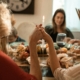 A family holding hands in prayer before a Thanksgiving dinner indoors with warm fall decor.